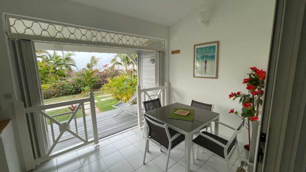 Zimmer mit einem Tisch und Stühlen sowie einer Tür zu einem Balkon in der Unterkunft Résidence Cocody in Sainte-Anne
