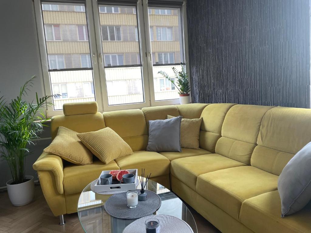 a yellow couch in a living room with windows at Grey Gucci Apartment City Center in Warsaw