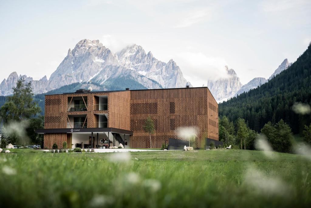 a building with mountains in the background with green grass at Aparthotel Gamz in Sesto