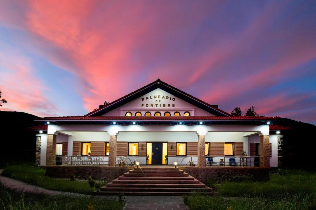 un edificio con una puesta de sol en el fondo en Villa rural Balneario de Fontibre en Fontibre