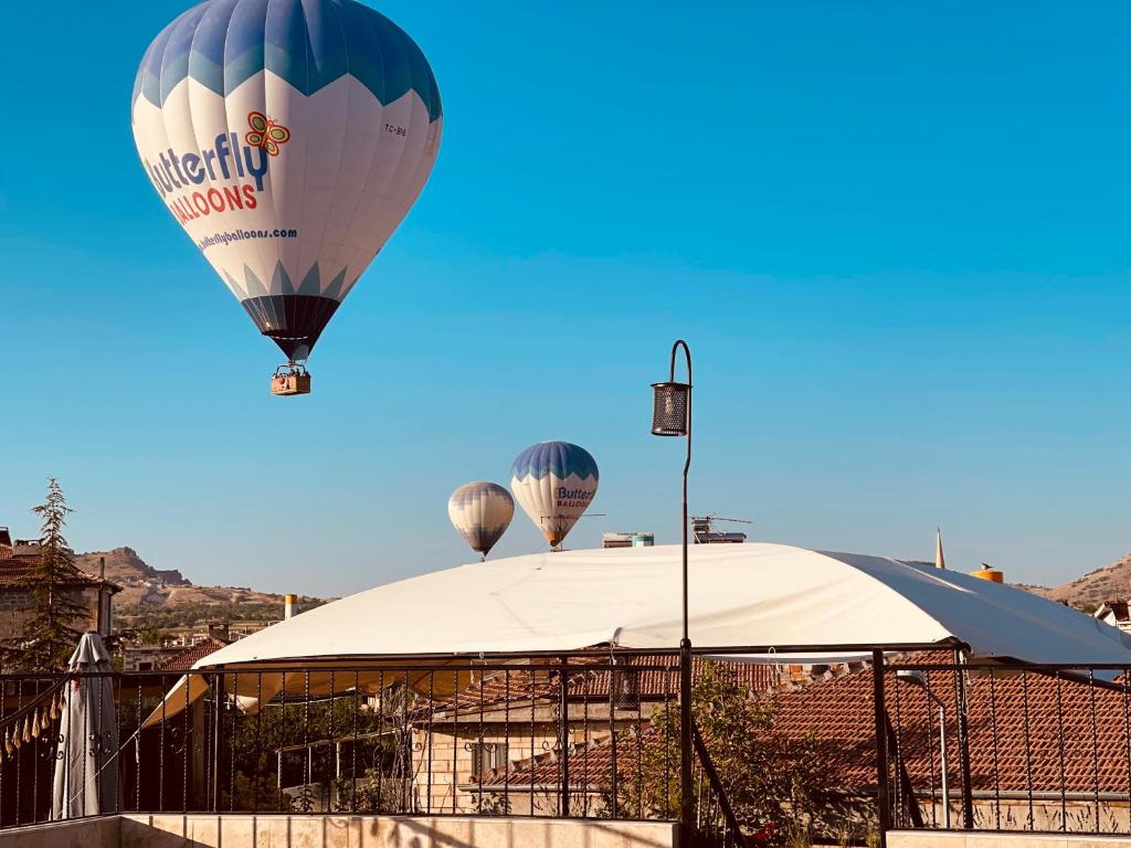 een groep heteluchtballonnen die over een gebouw vliegen bij Anatolia Raymonde Cave House in Uchisar