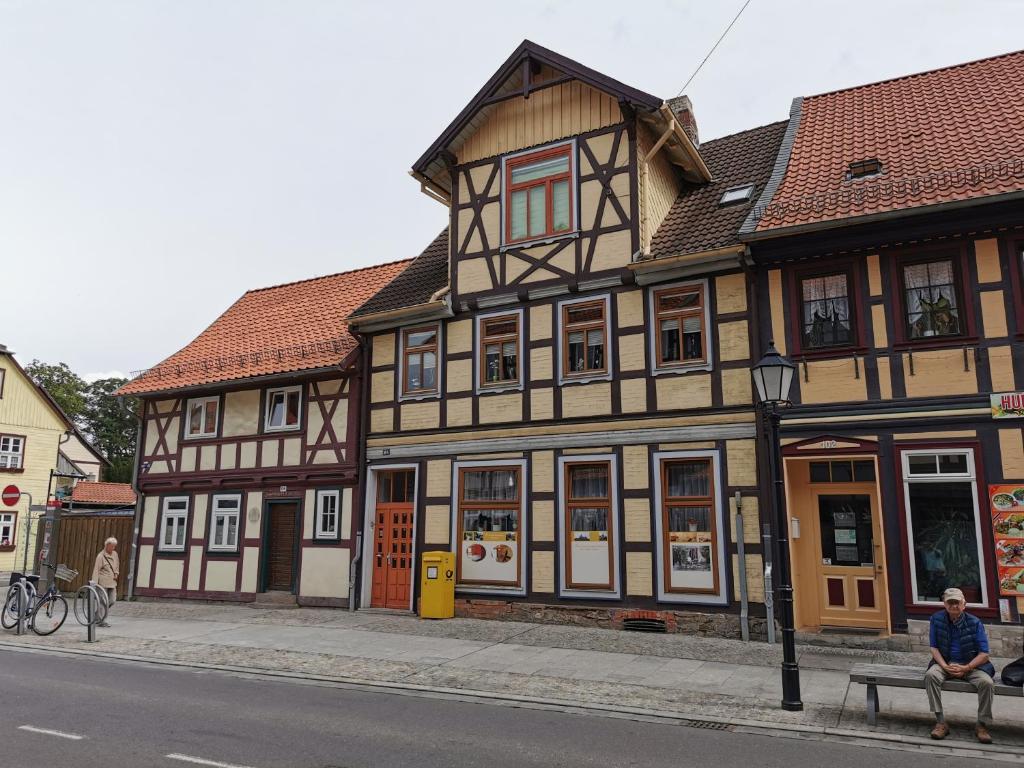 a man sitting on a bench in front of a building at Ferienwohnung Wetzig W1 - Breite Straße 104 Wernigerode in Wernigerode