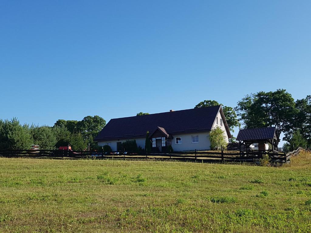 uma casa com uma cerca e um campo em frente em Gościniec Tymawa em Tymawa