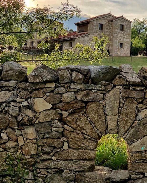 a stone wall in front of a house at LA SOLANILLA -Casas Rurales in Torre Val de San Pedro