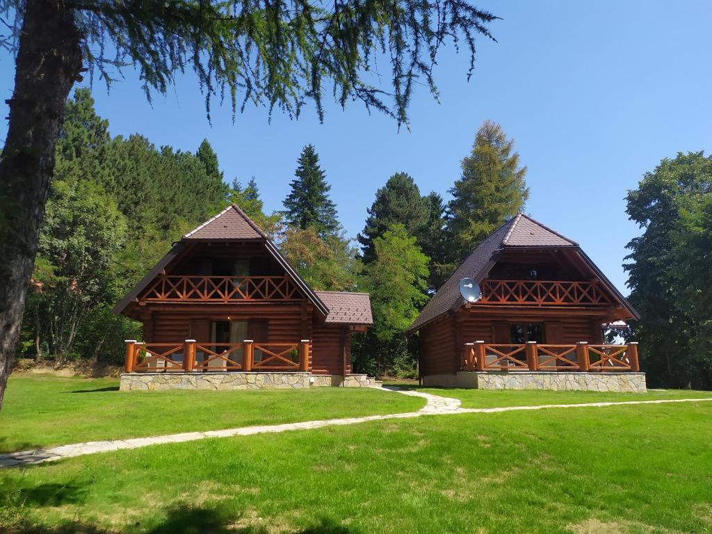 two large wooden buildings in a field with trees at Brvnare Park Borova in Zlatibor