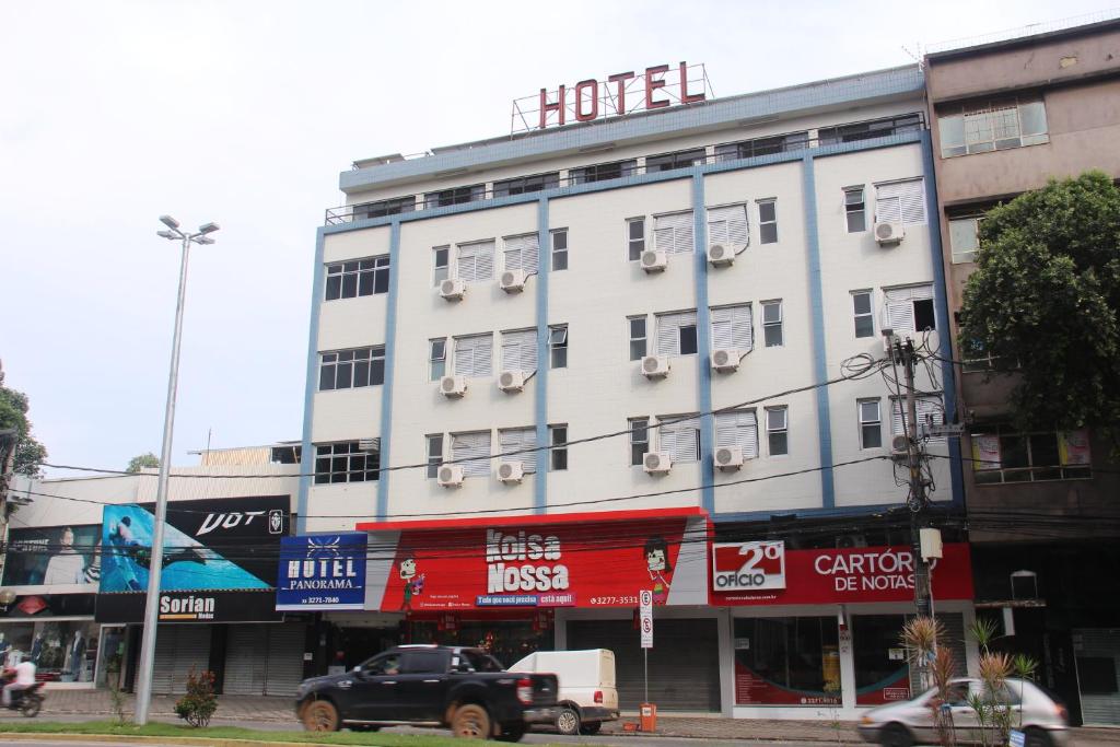 um grande edifício branco numa rua da cidade com carros em Panorama Hotel em Governador Valadares
