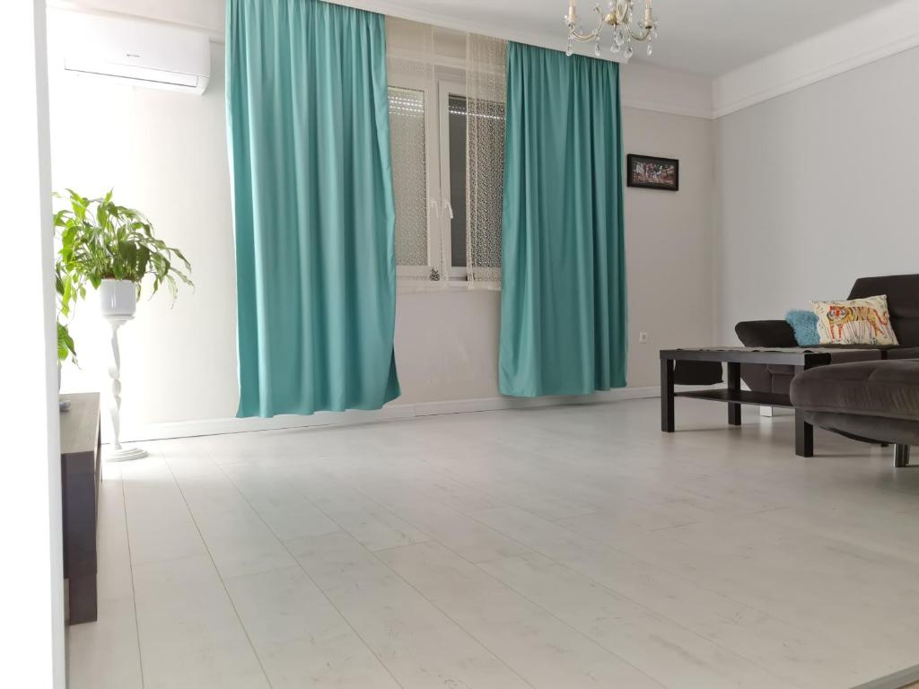 uma sala de estar com cortinas verdes e uma mesa em Come.in em Kiskunfélegyháza