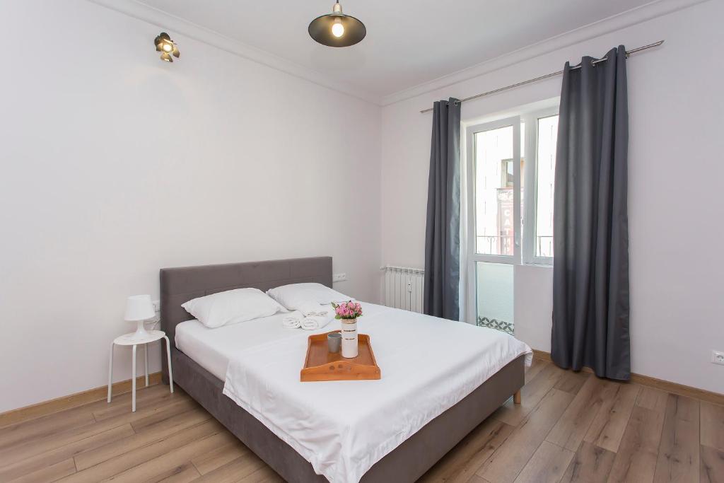 a white bedroom with a bed and a table with flowers on it at Sunny and Modern 1BDR Apartment in the Center in Sofia
