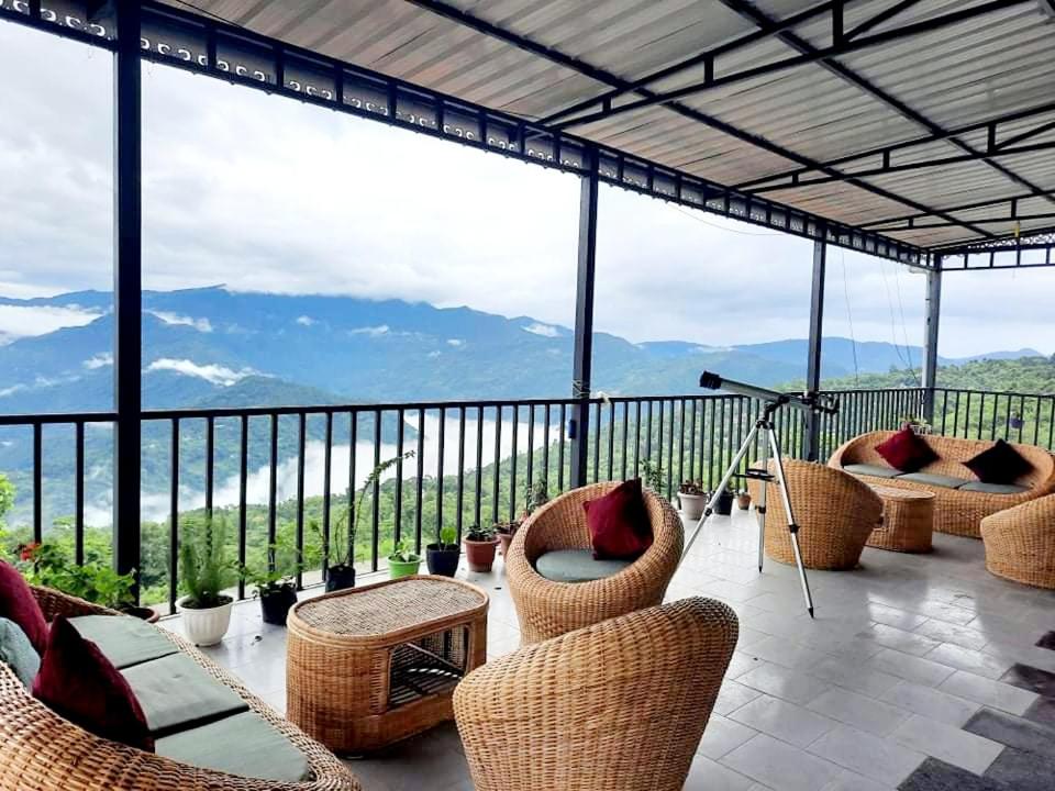a patio with chairs and tables and a view of mountains at Kalimpong Sunrise-Inn Homestay in Kalimpong