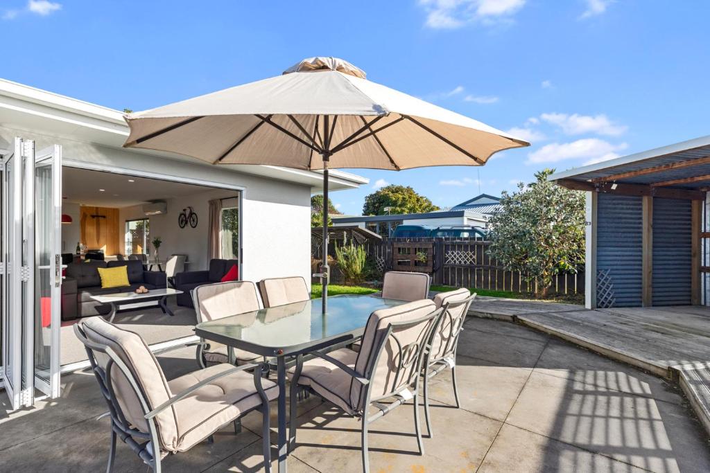 a table and chairs with an umbrella on a patio at Lazy Sun Daze - Papamoa Holiday Home in Papamoa