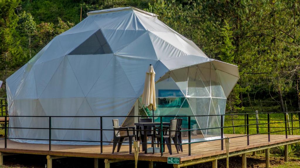 a tent with a table and chairs on a deck at La Quinta Dimensión Glamping Resort in El Peñol