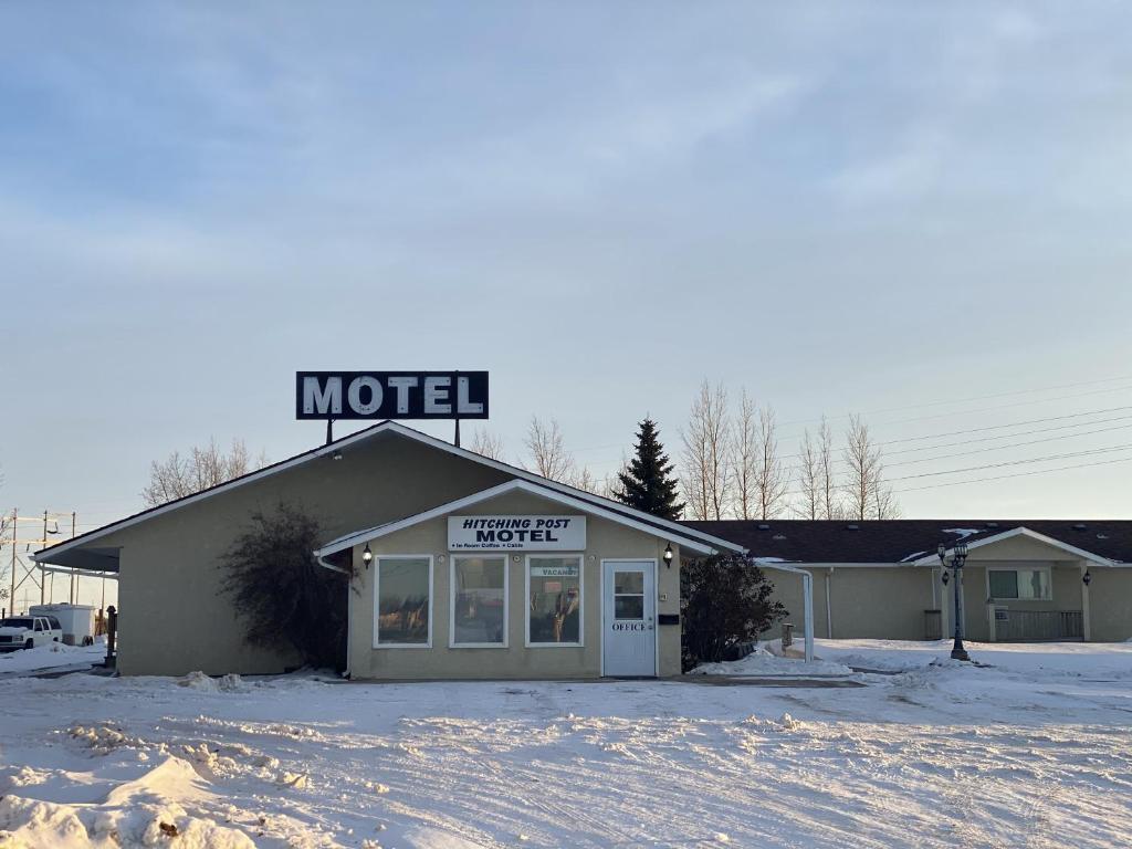 a motel sign on the top of a building in the snow at Hitching Post Motel in North Battleford