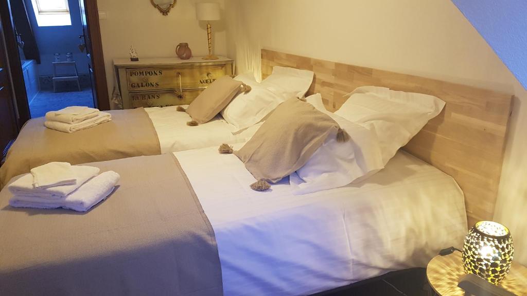2 camas en una habitación con sábanas y almohadas blancas en Les Toits de Turckheim en Turckheim