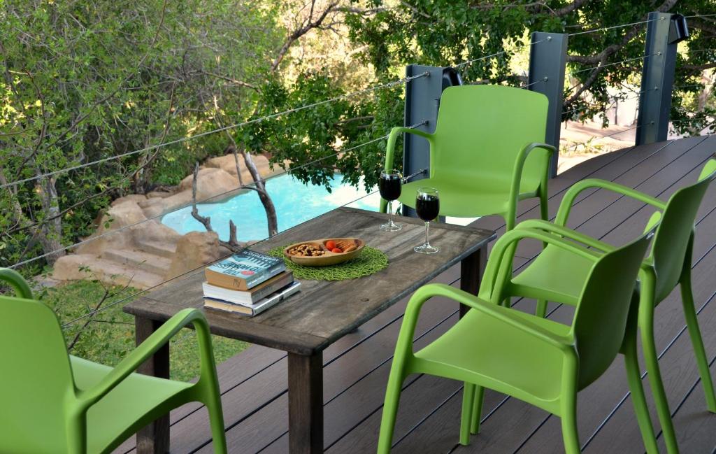 a table and chairs on a deck with a pool at Greenfire Game Lodge in Balule Game Reserve