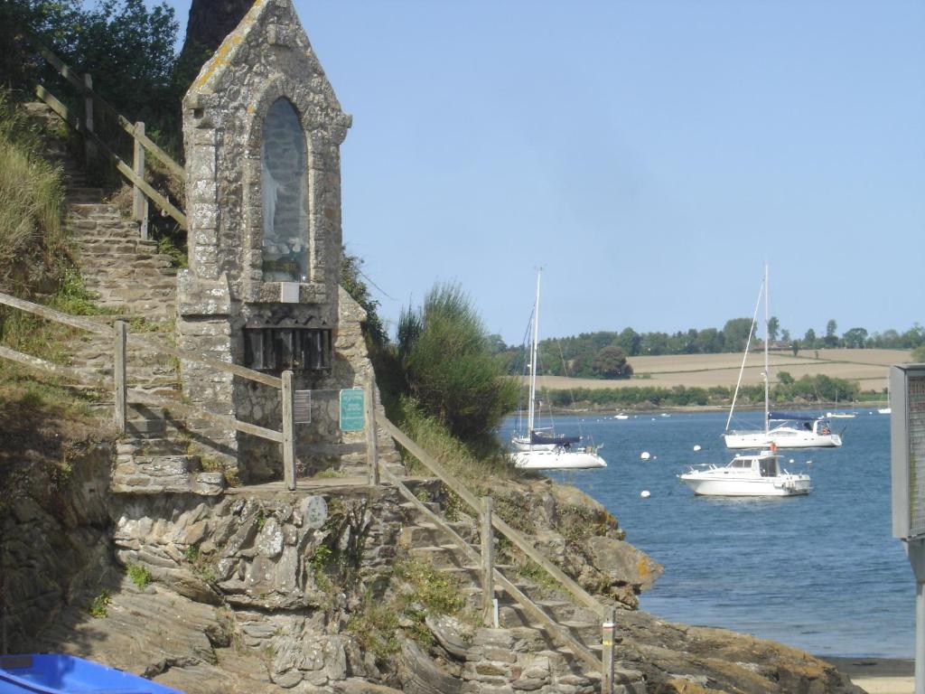 OG Gîte في Le Minihic-sur-Rance: كنيسة قديمة على جانب نهر مع قوارب