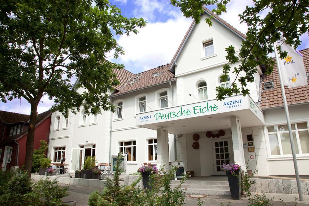 Un bâtiment blanc avec un panneau indiquant un nouveau partenariat définit le principal aîné dans l'établissement Akzent Hotel Deutsche Eiche, à Uelzen