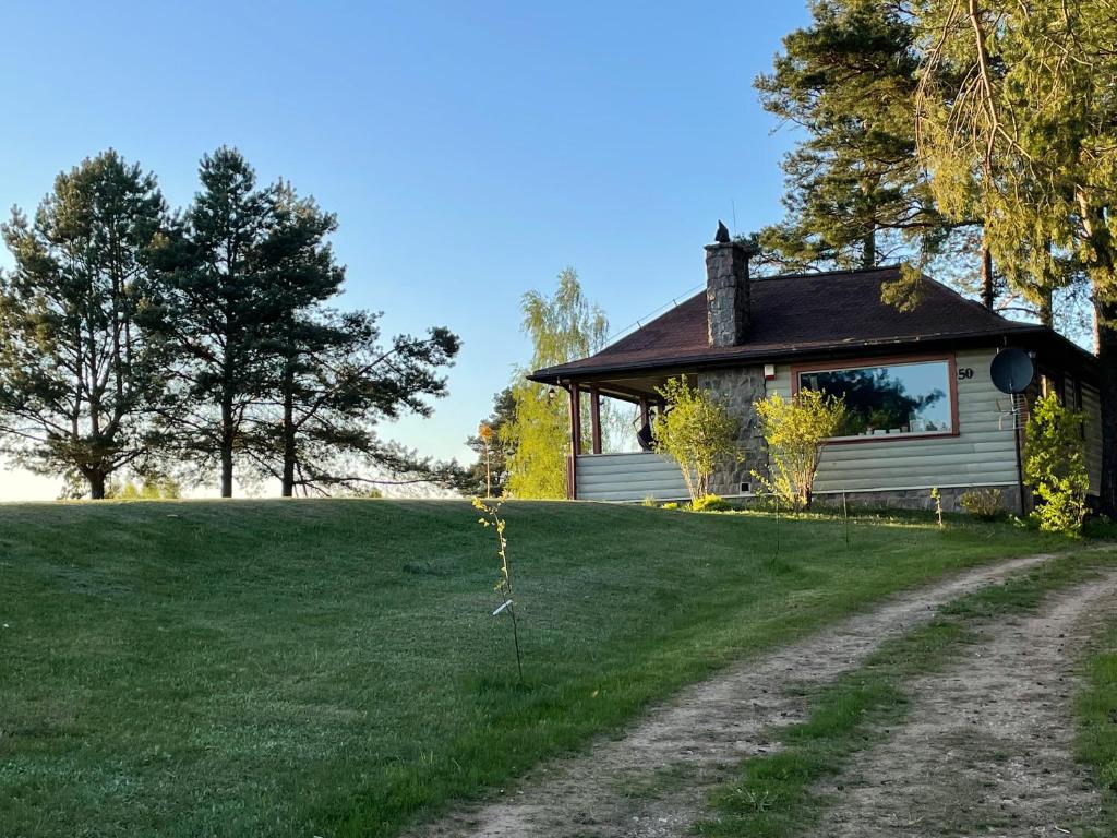 a house on a field with a dirt road in front at wietrznie-wichrowe wzgórze in Wólka Ratowiecka