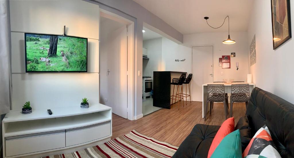 uma sala de estar com um sofá e uma televisão na parede em 707- Apartamento Encantador, amplo e decorado, quarto, sala, cozinha, mobiliario moderno, cozinha completa com utensílios , Excelente vista da cidade e localização privelegiada no bairro Bigorrilho em Curitiba