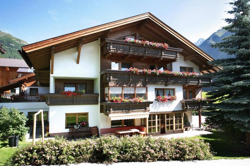 un grand bâtiment avec des boîtes de fleurs sur les balcons dans l'établissement Landhaus Sepp Santer, à Sölden