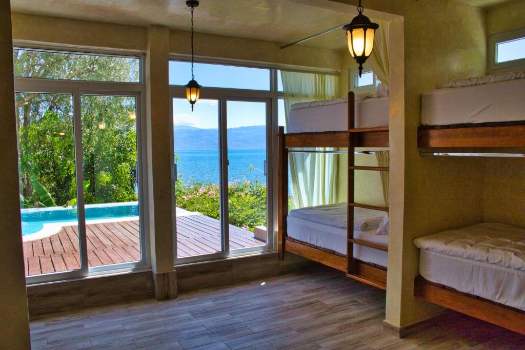 a bedroom with bunk beds and a view of the ocean at Casa Lobo Bungalows in San Pedro La Laguna