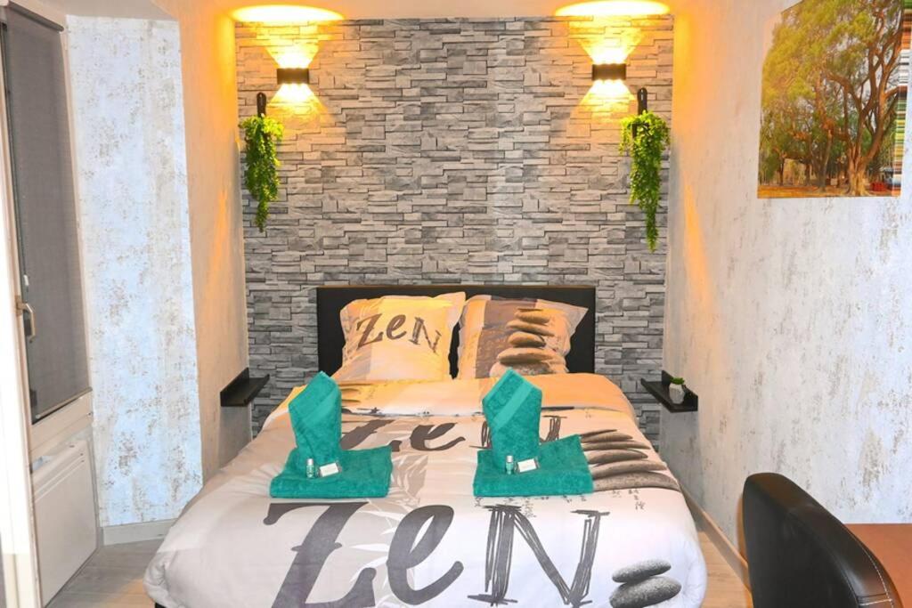 uma cama num quarto com uma parede de tijolos em ZEN Appartement 10mn CDG Airport em Villeneuve-sous-Dammartin