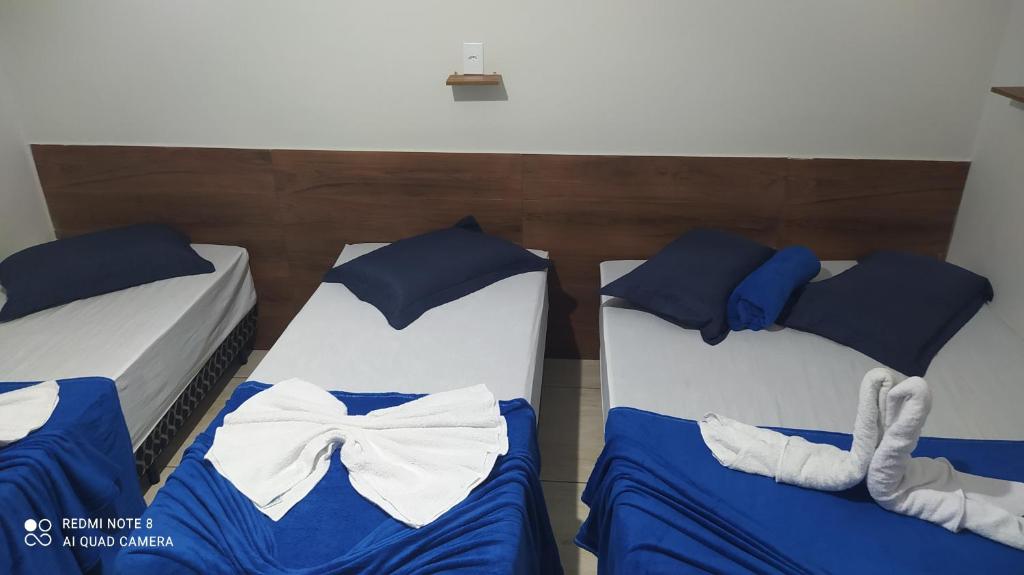 Dos camas con sábanas azules y una pajarita. en Pousada Quarto com frigobar,ar e garagem gratuita, en Aparecida
