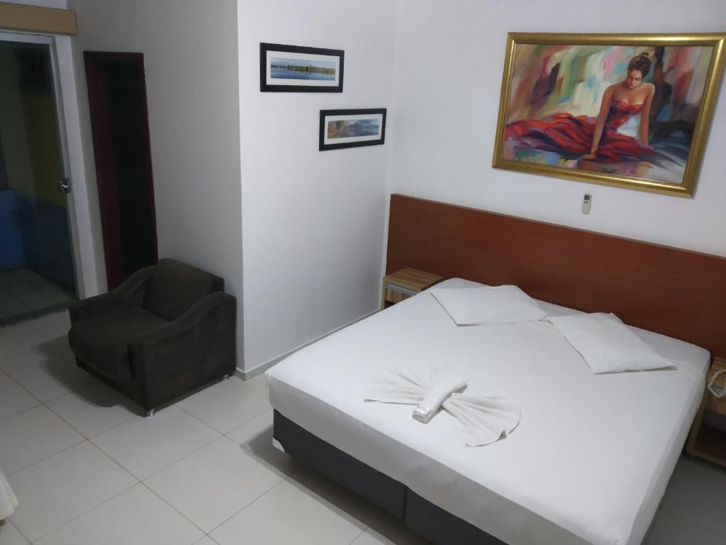 a bedroom with a bed and a chair and a painting at Hotel Iguaçu in Dionísio Cerqueira