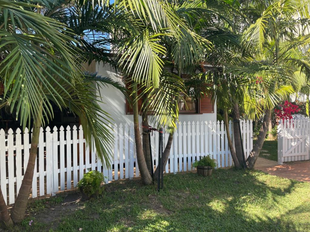 uma cerca branca com palmeiras em frente a uma casa em Bongaree Ocean Villa em Bongaree