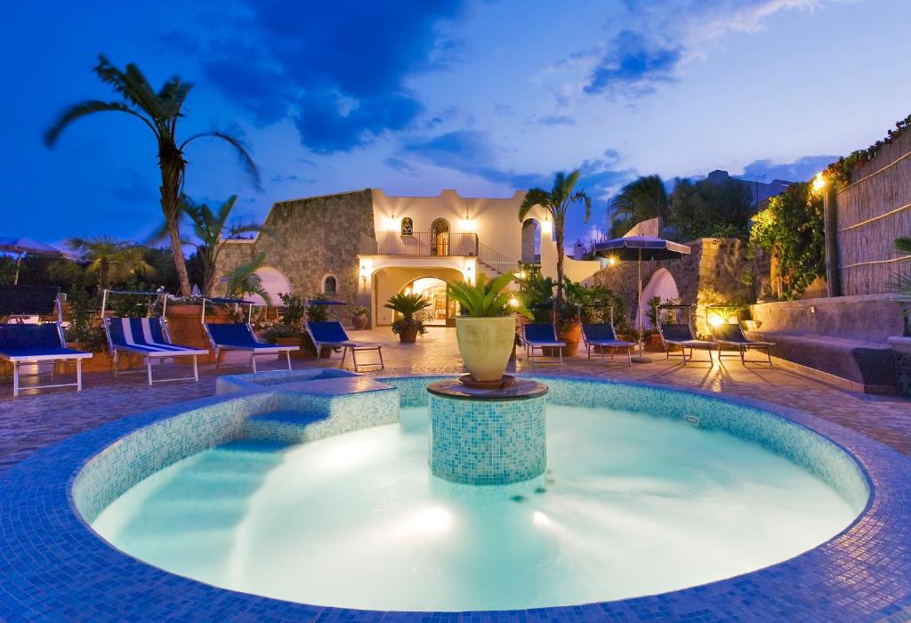 una piscina en un patio con sillas y una casa en Hotel Belvedere, en Isquia