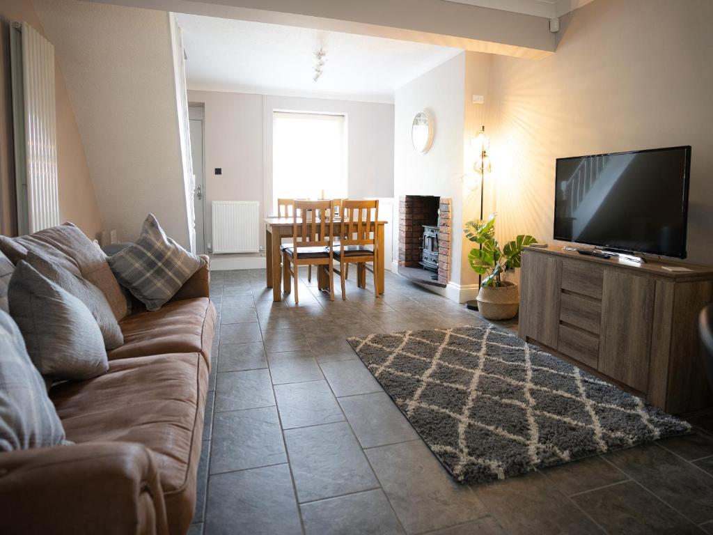 a living room with a couch and a flat screen tv at Tramway Cottage in Llandudno