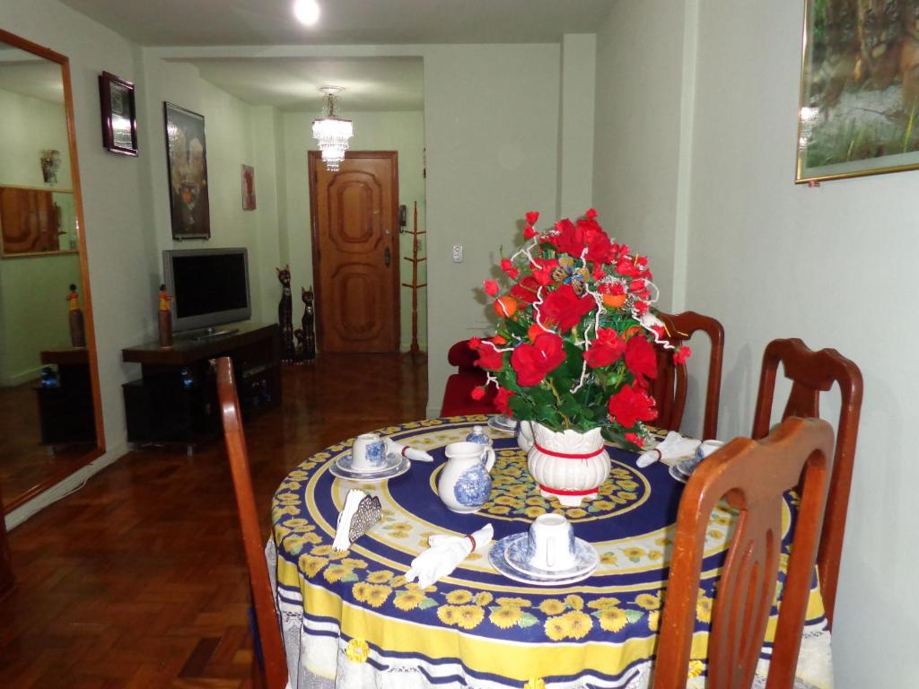 una mesa con un jarrón de flores rojas. en Rio Apartamento - Copacabana, en Río de Janeiro