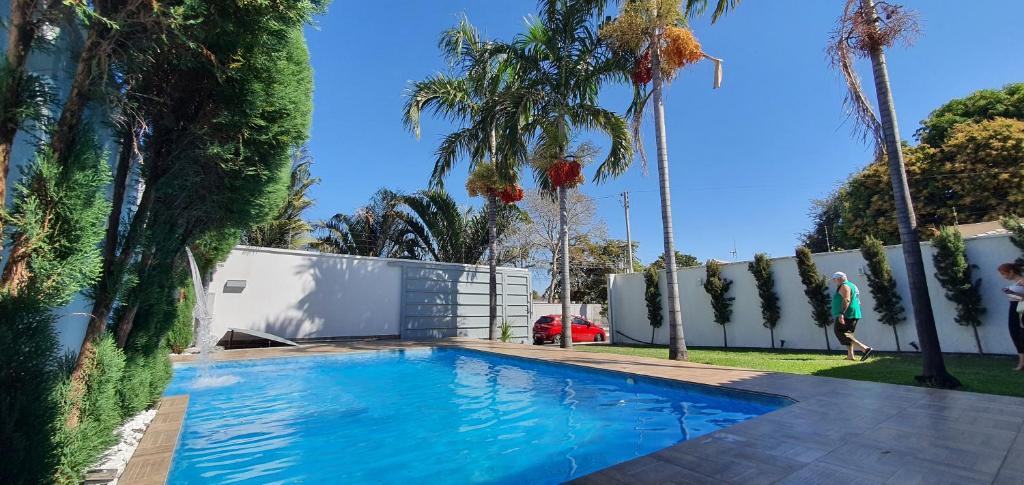 a swimming pool in a yard with palm trees at Casa Temporada Aruanã Rio Araguaia in Aruanã