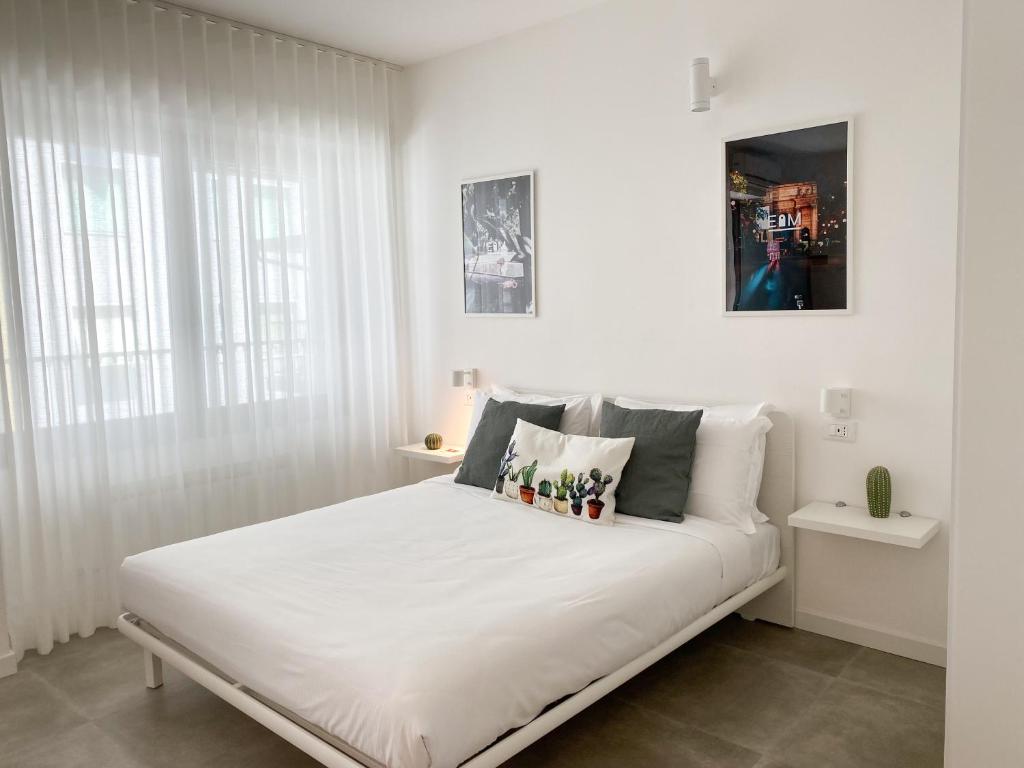 a white bedroom with a large white bed with pillows at Easy Milano Apartment Navigli in Milan