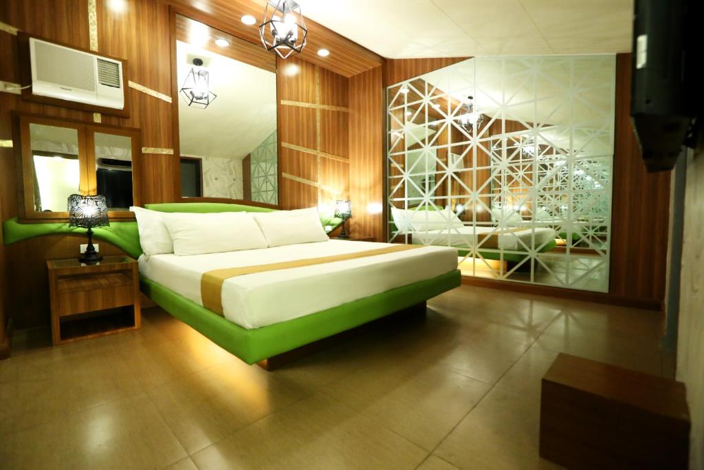 Hotel Ava Cuneta في مانيلا: غرفة نوم بسرير اخضر ومرآة