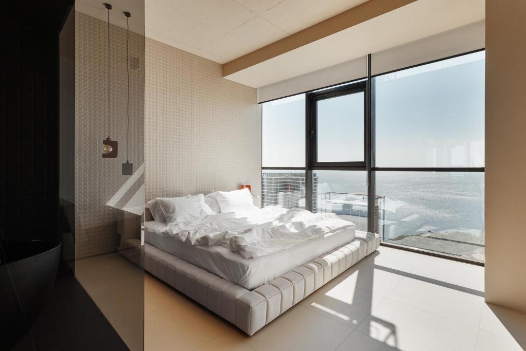 Sea and Sky Apartment في أوديسا: غرفة نوم بسرير ونافذة كبيرة