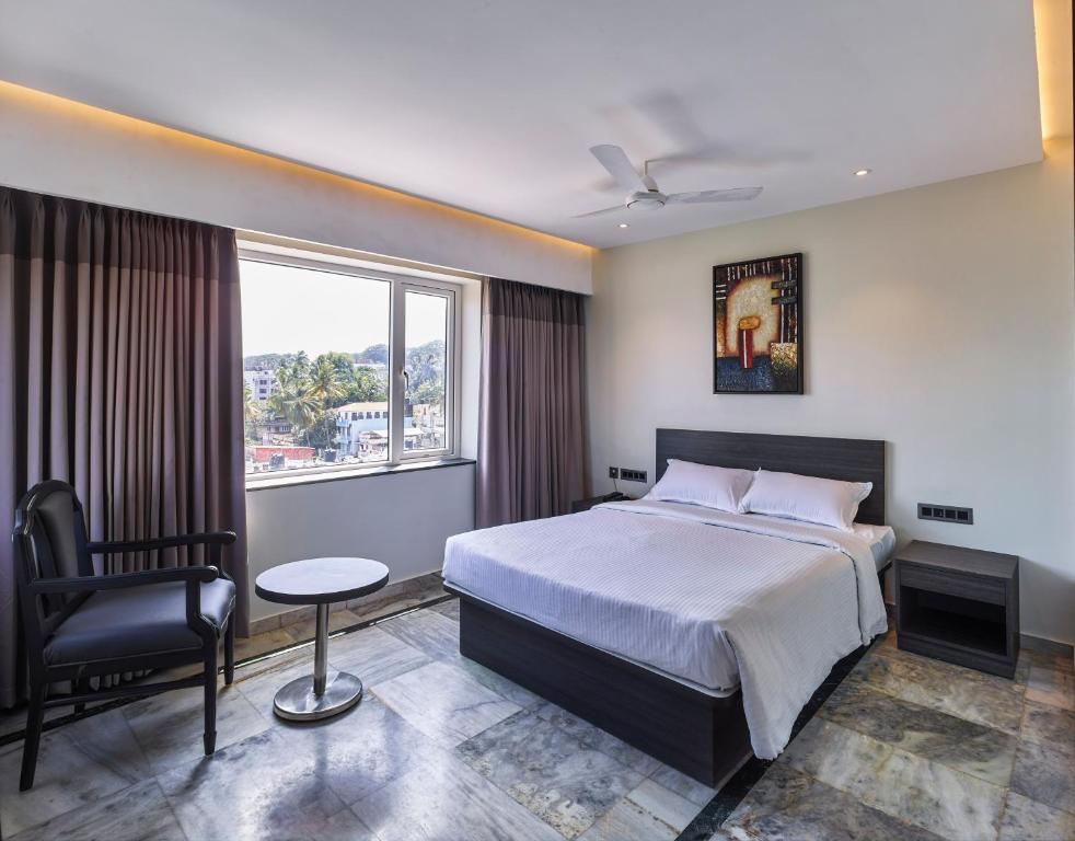 1 dormitorio con 1 cama, 1 silla y 1 ventana en Ariya Nivaas A Vegetarian Hotel, en Trivandrum