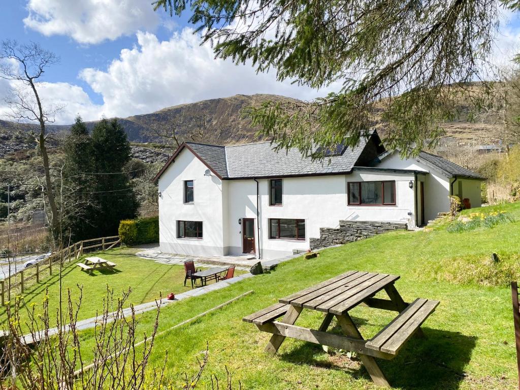 a white cottage with a picnic table in front of it at Stiniog Lodge in Blaenau-Ffestiniog