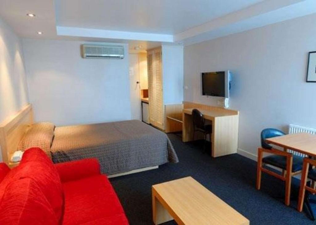 a hotel room with a red couch and a bed at Richmond Henty Hotel in Portland