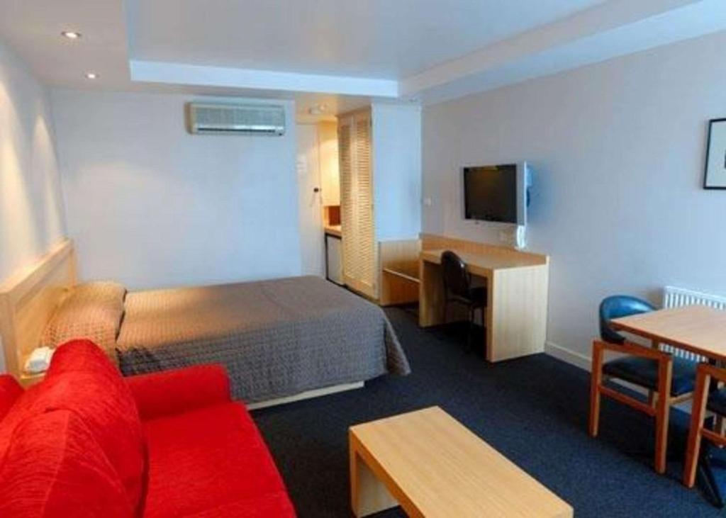 a hotel room with a red couch and a bed at Richmond Henty Hotel in Portland
