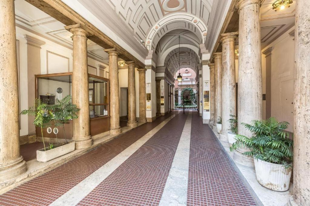 a hallway of a building with columns and plants at Magnifico Rome in Rome