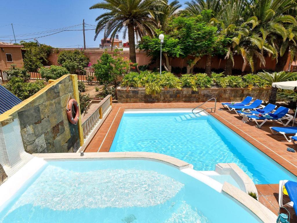 a large swimming pool with chairs and a person jumping into it at Rural Village Salobre in Maspalomas