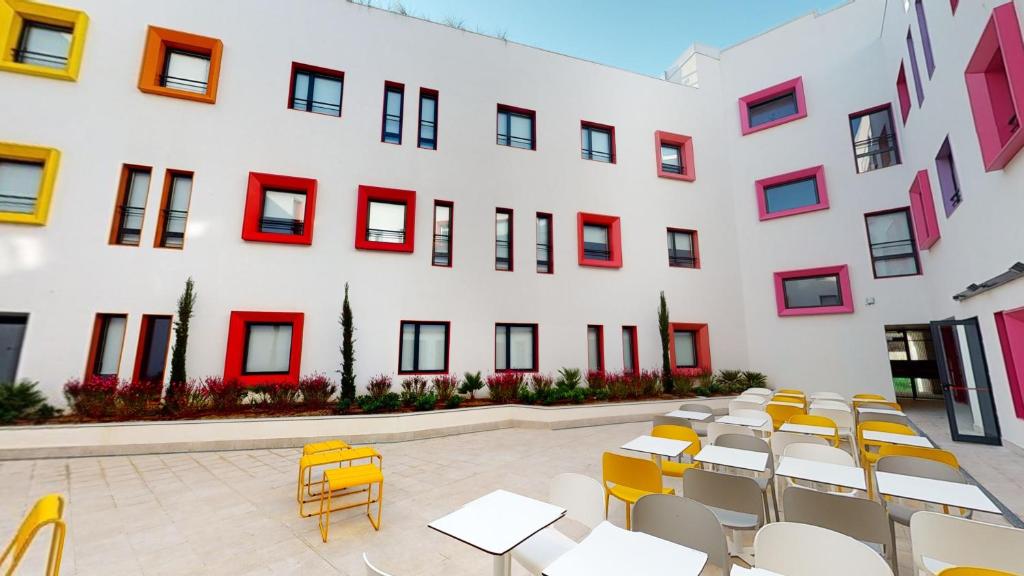 Residencia Universitaria Málaga Centro في مالقة: مبنى امامه طاولات وكراسي