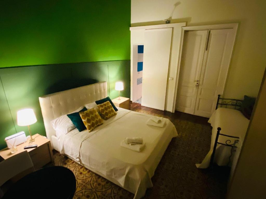 een slaapkamer met groene muren en een bed met 2 lampen bij Al Castello in Catania