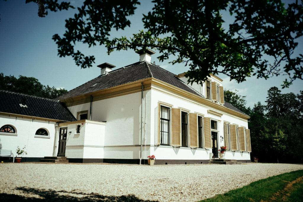 una vieja casa blanca con techo negro en Klein Soestdijk en Veenhuizen
