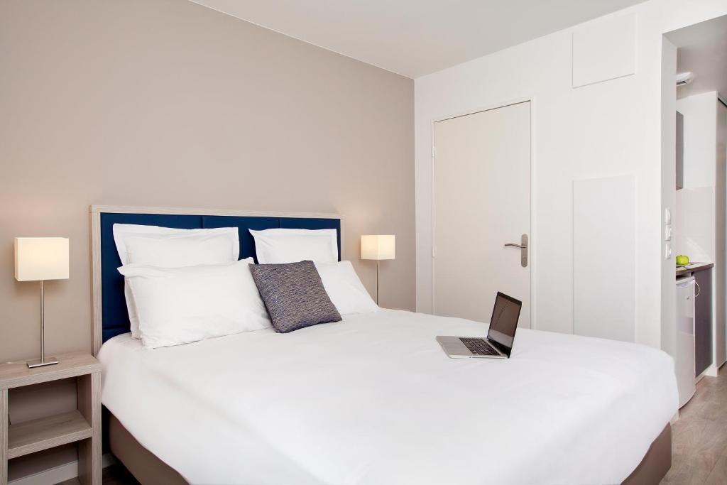 a bedroom with a white bed with a laptop on it at Séjours & Affaires Paris Bagnolet in Bagnolet