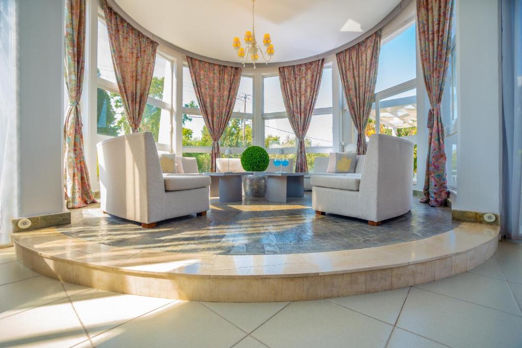 a lobby with two chairs and a table and windows at Happy Days Hotel, Adults Only in Theologos