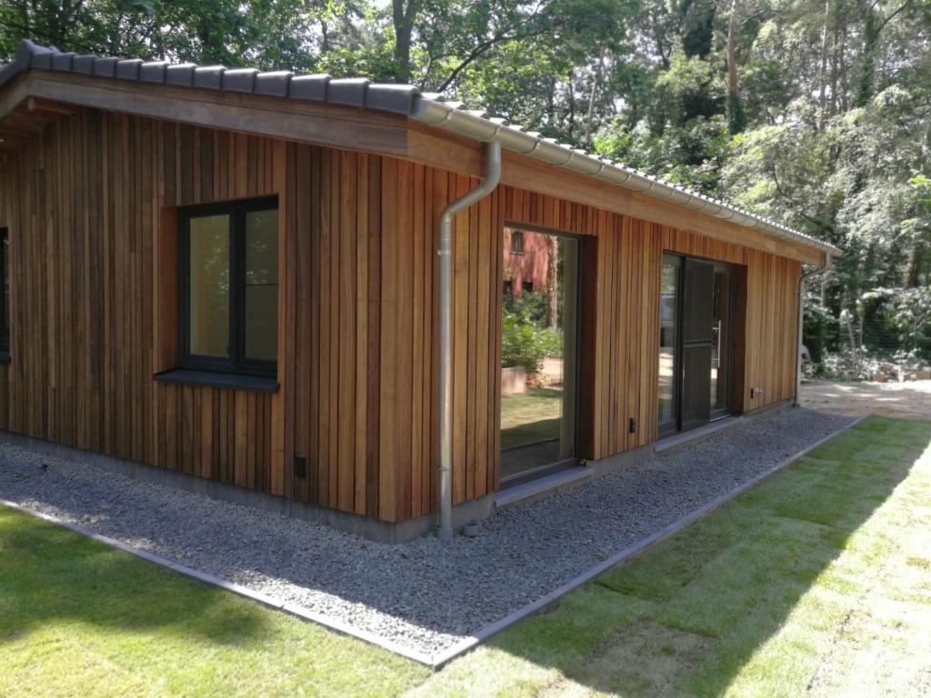 a small wooden building with windows in a yard at Hogenberg Heiken Lichtaart / Kasterlee in Lichtaart