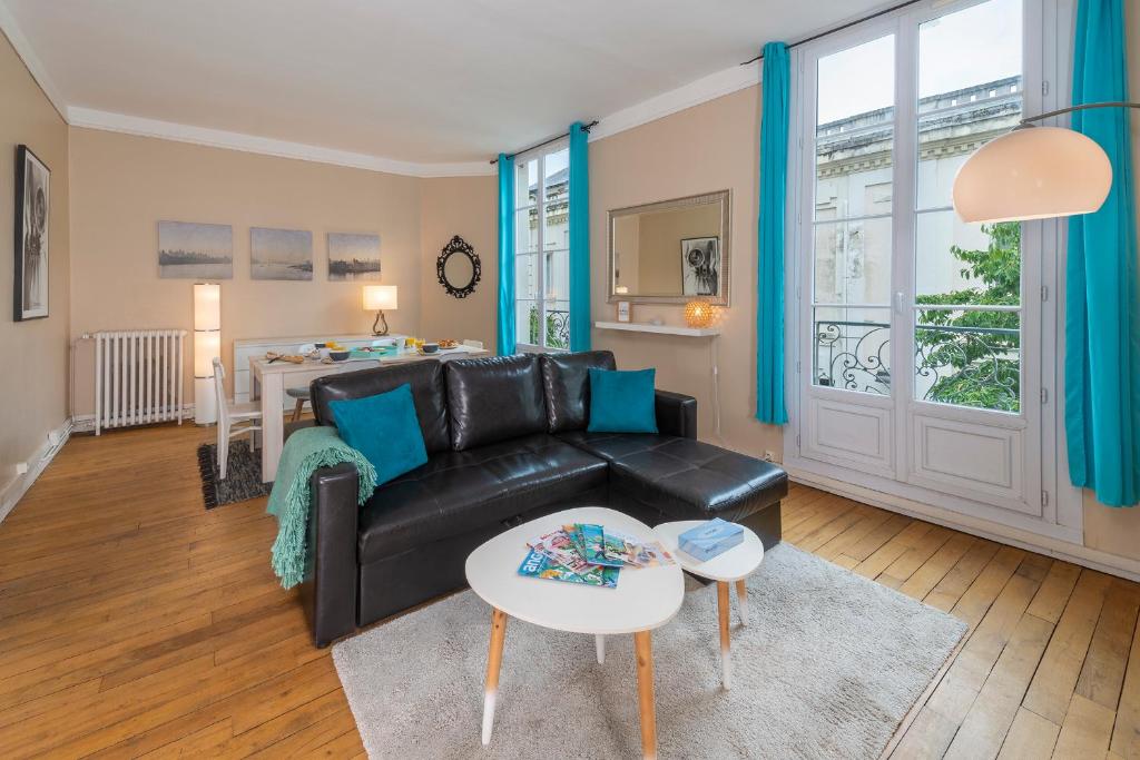 ein Wohnzimmer mit einem schwarzen Ledersofa und einem Tisch in der Unterkunft Appartement Coeur de Ville rue Saint-Laud in Angers