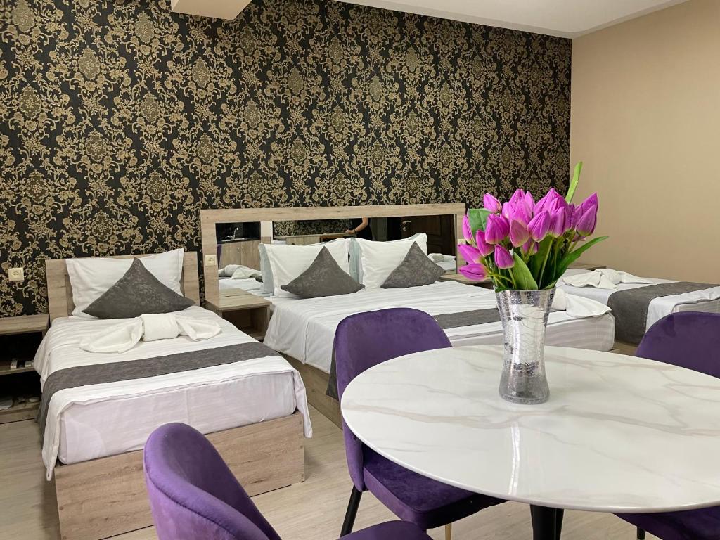 a hotel room with two beds and a table with purple chairs at Kamar Hotel Ijevan in Ijevan