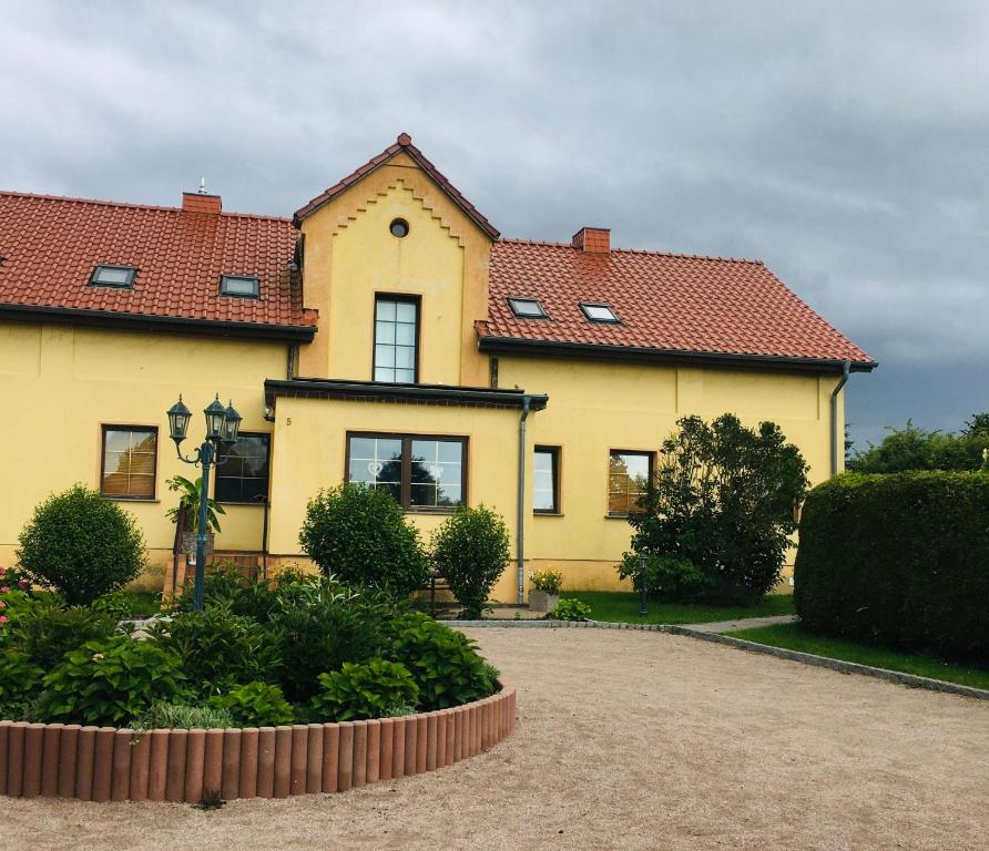 une maison jaune avec un toit rouge dans l'établissement Ferienwohnung Heiligenhagen, à Satow